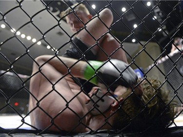 Mariusz Ksiazkiewicz, top, slams his fist into the throat of Micah Brakefield during the Queen City Coronation, an MMA event held at the Orr Centre in Regina on Saturday March 12, 2016.