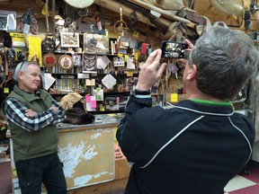 Scott Robertson looks on as Saskatchewan Party leader Brad Wall (right), takes a photo at Robertson Trading Post during a campaign stop in La Ronge on Monday.