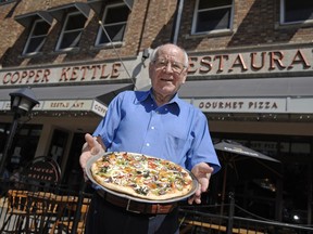 Robert Gardikiotis, owner of The Copper Kettle, holds up one of the signature pizzas in 2011.