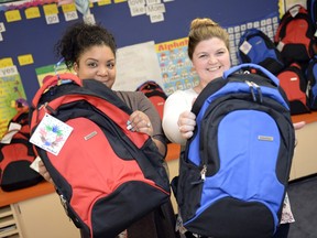 Salema Kifle, left, ELA teacher, and Jocelyn Xhaferi, Grade 2 teacher, at George Lee Elementary School hold up backpacks they're delivering to new immigrant students, including about 200 Syrian kids, coming into Regina Public Schools.