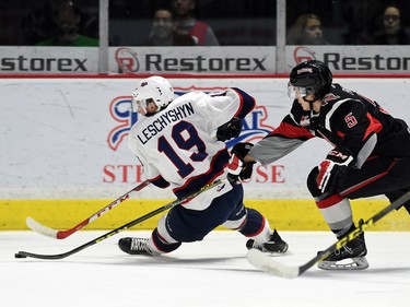 Jake Leschyshyn (L) with the Regina Pats moves the puck past by Colin Paradis (R) with the Moose Jaw Warriors during WHL hockey action at the Brandt Centre in Regina on March 11, 2016.