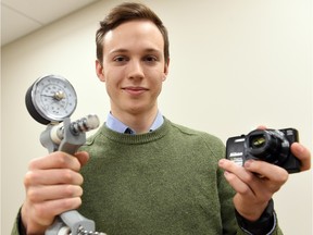 Dallas Novakowski is a University of Regina master's psychology student. He's shown with a device to measure handgrip strength and a camera to study people's facial symmetry.