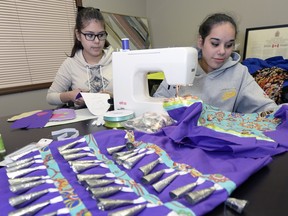 Michaela (left) and Alysha Pache are finishing off their younger sister's powwow regalia, a jingle dress. The three sisters will be initiated into the powwow circle on Saturday.