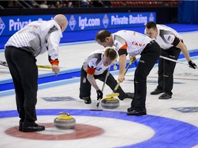 Regina product Ben Hebert (right) watches as Team Canada third Marc Kennedy brushes a stone during Sunday's gold-medal game at the world men's curling championship.