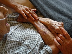 Hospice volunteers caress the hands of a terminally ill patient at the Hospice of Saint John in Lakewood, Colorado.
