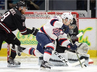 Red Deer Rebels Kayle Doetzel, left, tries to tie up Regina Pats Sam Steel in front of Rebels goalie Trevor Martin in WHL playoff action at the Brandt Centre in Regina on Tuesday.