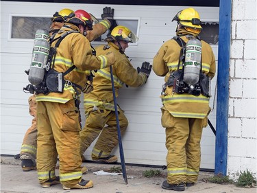 Firefighters take care of a garage door while fighting a fire at Wilf's Autobody & Painting Ltd. on the 1600 block of St. John Street.