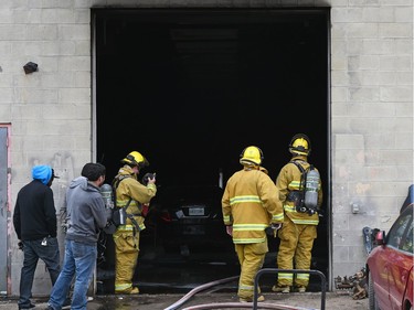 Firefighters look inside Wilf's Autobody & Painting Ltd. as fire damaged the building Tuesday afternoon.