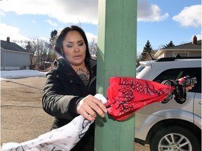 Shawna Oochoo ties bandanas representing the three gangs in the North Central area onto a streetlight in the 700 block of Garnet Street, the site of a homicide.