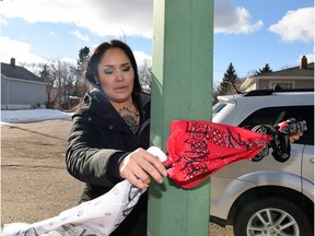 Shawna Oochoo ties bandanas representing the three gangs in the North Central area onto a streetlight in North Central. Oochoo and North Central community members have established White Pony Lodge and plan to start a street patrol this summer to curb violence in the area.