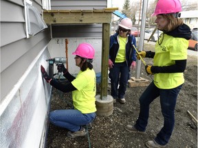 Women working on Habitat for Humanity homes on Edgar Street in Regina Wednesday. The group consists of 200K Women members that come together each year to assist with the builds. Here (L-R) Yvonne Slovodian, Kim Oberthier, and Glenda Heavisides attach Parging screen to a home.