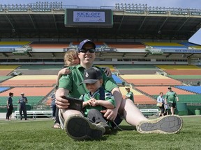 Casey Schroth sits on the turf with his kids Caylee and Caden at a Mosaic Stadium farewell season kickoff event in Regina on May 21, 2016.