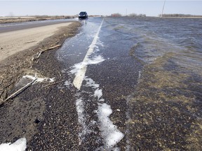 In this 2011 photo, vehicles are using one lane to pass through flood waters flowing over Highway 16 near Lanigan, by the Quill Lakes.