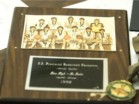 A photograph of the1983 La Loche Basketball team with their trophies and awards from their season.