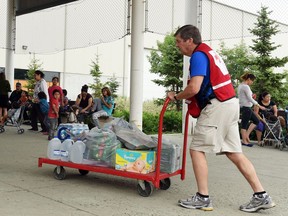 REGINA, SK: JULY 02, 2015 --  Red Cross volunteers Kelly Moens (L) and Doug Leask wheel in supplies at the Credit Union EventPlex (soccer centre) in Regina on July 02, 2015 where evacuees from the Northern Saskatchewan forest fires are being housed.   (DON HEALY/Regina, Leader-Post) (Story by Taylor Rattray) (NEWS)