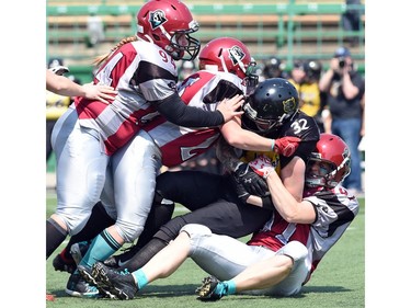 (L-R Amery Deren, Shelby Moran and Ciara Cullen all with the Regina Riot bring down Katherine Unger (C) with the Winnipeg Wolfpack during a football game at Mosaic Stadium in Regina.