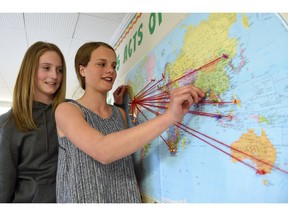 Kyle Young-Hamel (L) and Emily Hultgren (R) both members of the Argyle Elementary School environmental club pose beside a map of the world where students where able to get over 1000 people to participate in 31 countries in an act of environmental conservation. It could range from a students aunt in New Zealand composting lawn cuttings to another person recycling plastic bottles, paper and electronics.