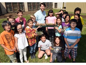 Executive director of the North Central Community Association, Michael Parker (C) at the North Central Community Association Gardens with students ready to plant seedlings from Sacred Heart Community School in Regina.