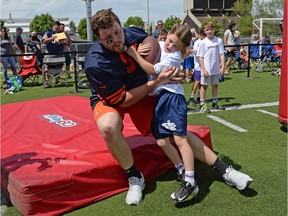 Chicago Bears offensive tackle Martin Wallace, left, is hit by Kiera Muckelt-Landry during a drill at the NFL's Play 60 initiative at U of R Field on Saturday.