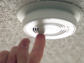 A homeowner tests a smoke alarm to ensure it is in good working order.