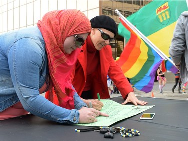 Debra Schubert and Susan Petryk prepare a sign at the Queen City Pride Parade in Regina, Sask. on Saturday June. 25, 2016.