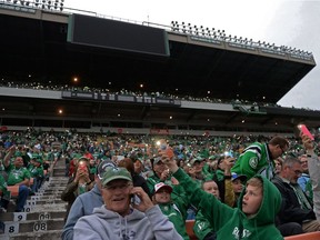 Fans hold up their mobile phones to provide illumination during a power outage Saturday night, when the Saskatchewan Roughriders played host to the B.C. Lions in CFL pre-season action.