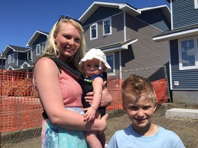 (L-R) Aleesa Blight and her two children, Selena, 6-months, and Braxton, 6, stand in front of their new home in the Eastview area. Habitat for Humanity handed Blight the keys to their new home at a ceremony, on Tuesday.