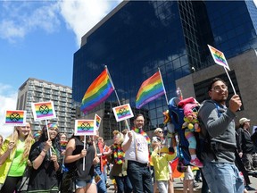 People hold colourful flags and signs during the Queen City Pride Parade in Regina, Sask. on Saturday June. 25, 2016. MICHAEL BELL