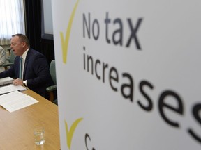 Finance Minister Kevin Doherty speaks to media alongside a sign about no tax increases in his first budget.