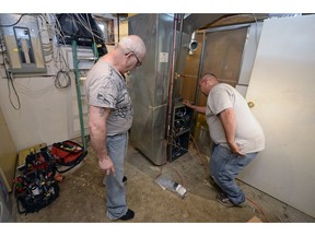 Homeowner Michael Peters, left, listens while Trevor Gerlach of All-Premium Plumbing and Heating talks about the installation of Peters' new furnace in Regina on Monday.  Some low-income homeowners receiving up to $10K in energy efficient retrofits as part of the Home Energy Legacy Program (HELP).