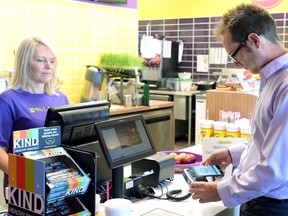 Booster Juice owner Jodie King, left, and credit union member Shawn McNall demonstrate an Android -based smart phone app allowing customers to use their smart phones to make a payment in Regina on Tuesday.