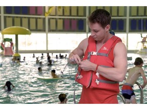 Dan Carr, lead lifeguard at Sandra Schmirler Leisure Centre, pus on a personal flotation device in Regina on Tuesday.