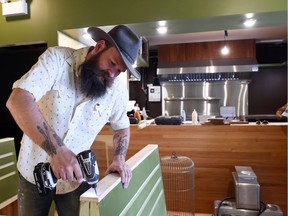 Neil McDonald works on installing booths at his new vegetarian diner.