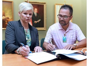 Minister Responsible for Corrections and Policing, Christine Tell (L) and Mark Fox, executive director at Fox Valley Counselling Services Inc., signing the contract for the Healthy Families Initiative at the Legislative building in Regina.