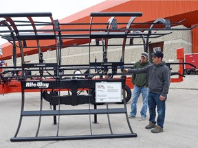 Todd Gallais (L) and Kole Riemer (R) both from White Fox, SK look over a Rite Way Bale Grapple at Canada's Farm Progress Show in Regina.  Rite Way Manufacturing Company has just entered into a licensing agreement with Haukaas Manufacturing to produce its products, the Bale Cart and Bale Grapple. The agreement will allow Rite Way to expand its customer base to include livestock farmers and hay producers.