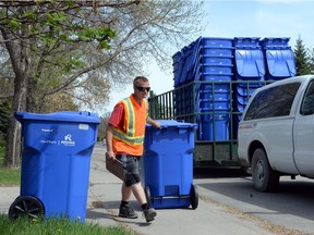 Workers unload blue bins for recycling in Regina in May 2013.