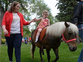 Alayna Nestman holds her daughter Lila's hand on a Discovery Ranch horse demonstration during Canada Day celebrations at Government House in Regina, Sask. on Friday July 1, 2016. Discovery Ranch provides equine therapy for those with mental health or developmental issues. MICHAEL BELL