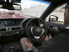 Look - no hands. An employee of Toyota Motor Corp., in an automated driving test vehicle during a test drive of Toyota's self-driving technologies in Tokyo 2015.