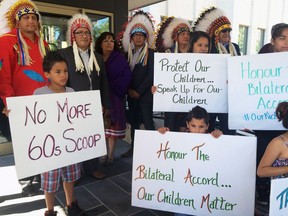Children hold signs along with members of the Saskatoon Tribal Council outside the courthouse in Regina on June 28.