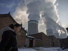 A Chinese resident walks out of her house next to a coal-fired power plant in Shanxi. China is the source of nearly a third of the world's total carbon dioxide (CO2) emissions, which contribute to global warming.