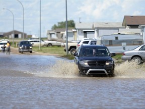 Vehicles head down a flooded road in Willow Park Gardens in Estevan on Monday.