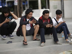 In this Monday, July 18, 2016 photo, people gaze at their smartphones as they play "Pokemon Go" in Jakarta, Indonesia. Indonesian authorities banned the playing of "Pokemon Go" from the presidential palace on Wednesday, July 20, 2016, as they voiced worries that the game could be a security risk.