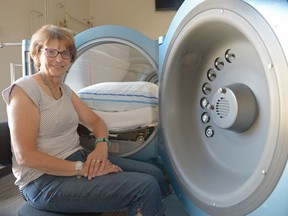 Judy Larsen sits at the entrance to a hyperbaric oxygen chamber at O2XY-wellness in Emerald Park, Sask.