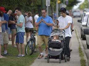 Kevin Parisien, centre left, and Mario Daigle, centre right, play Pokemon Go during a "lure-apolooza" along 13th Avenue in Regina on July 31, 2016.