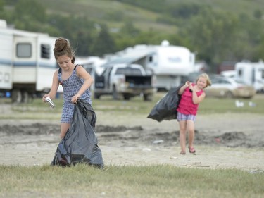 Megan Secuur, left, empties a crushed can while Mia Secuur hauls a bag of cans and bottles to collect the recycling money at the Craven Country Jamboree on Sunday. The girls' mum Janine Secuur (not pictured) says that the general camping area is not family-friendly, but other areas are. Secuur and her family are in Section 2, near the same people year after year.