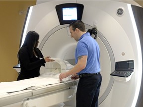 MRI technologists Priya Kumar, left, and Kevin Johannson stand beside a 1.5 Tesla large bore MRI machine at Mayfair Diagnostics in Regina in April.