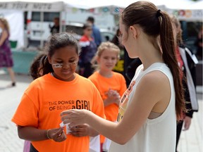 Tre-Ana Cope Quong, left, hands a body-positive note to Elene Wanner at the Regina Farmers' Market on Wednesday, part of the YWCA Power of Being a Girl camp.
