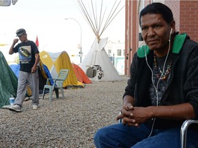 Robbin Whitecap, left, walks while Prescott Demas looks on at Colonialism No More Solidarity Camp outside of an Indigenous and Northern Affairs Canada office in Regina, Sask. on Sunday July 3, 2016.