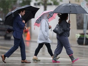 People take cover under umbrellas during the rainy lunch hour downtown Saskatoon on July 11, 2016.
