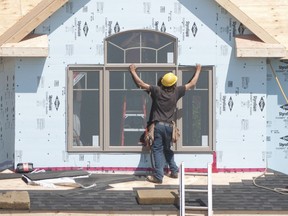 Residential construction sites can be hazardous places if safety regulations are ignored. An Ontario construction worker is shown installing a window on the second floor of a new home.